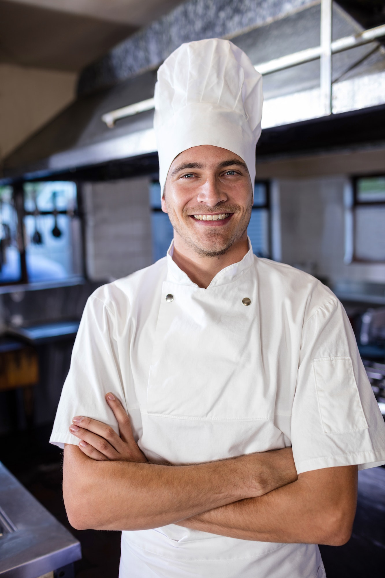 Male chef standing with arms crossed in kitchen